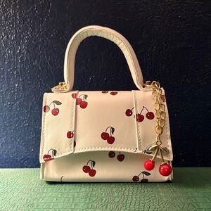 White mini-bag with red cherries and gold hardware